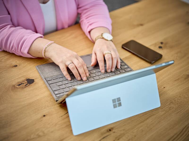 Das Foto zeigt eine Frau die Daten an einem Laptop eingiebt mit einer rosa Weste an