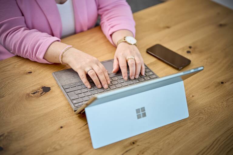 Das Foto zeigt eine Frau die Daten an einem Laptop eingiebt mit einer rosa Weste an