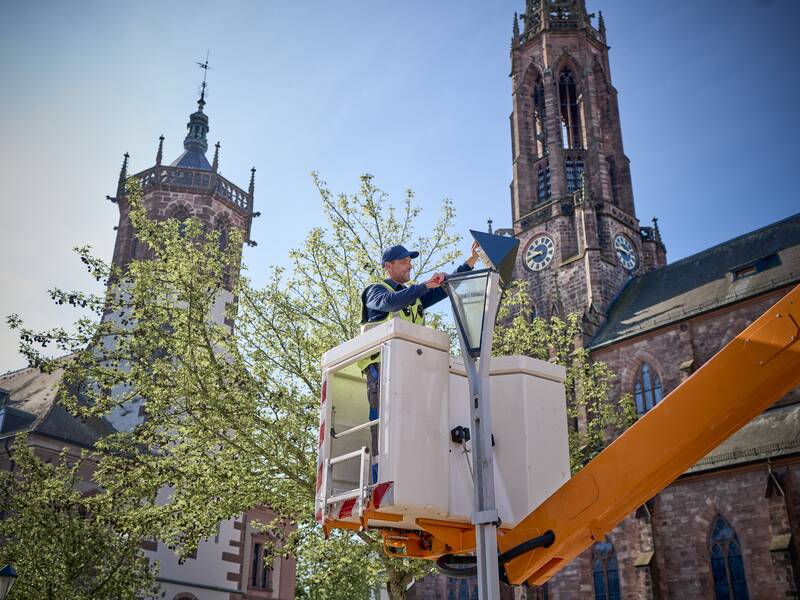 Ein Mann arbeitet in einem Staiger an einer Straßenlaterne vor der katholischen Kirche in Bühl.