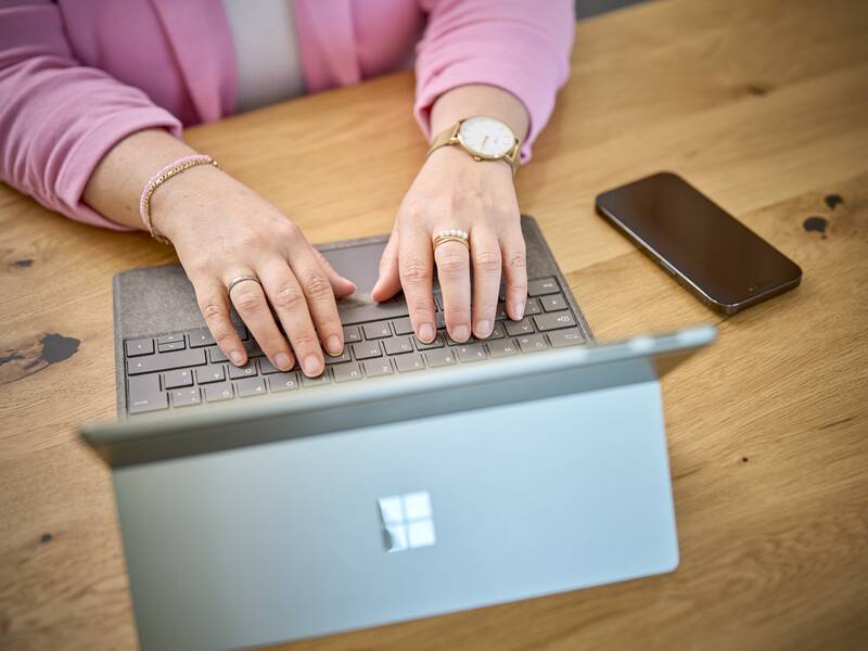Das Foto zeigt eine Frau die Daten an einem Laptop eingiebt mit einer rosa Weste an